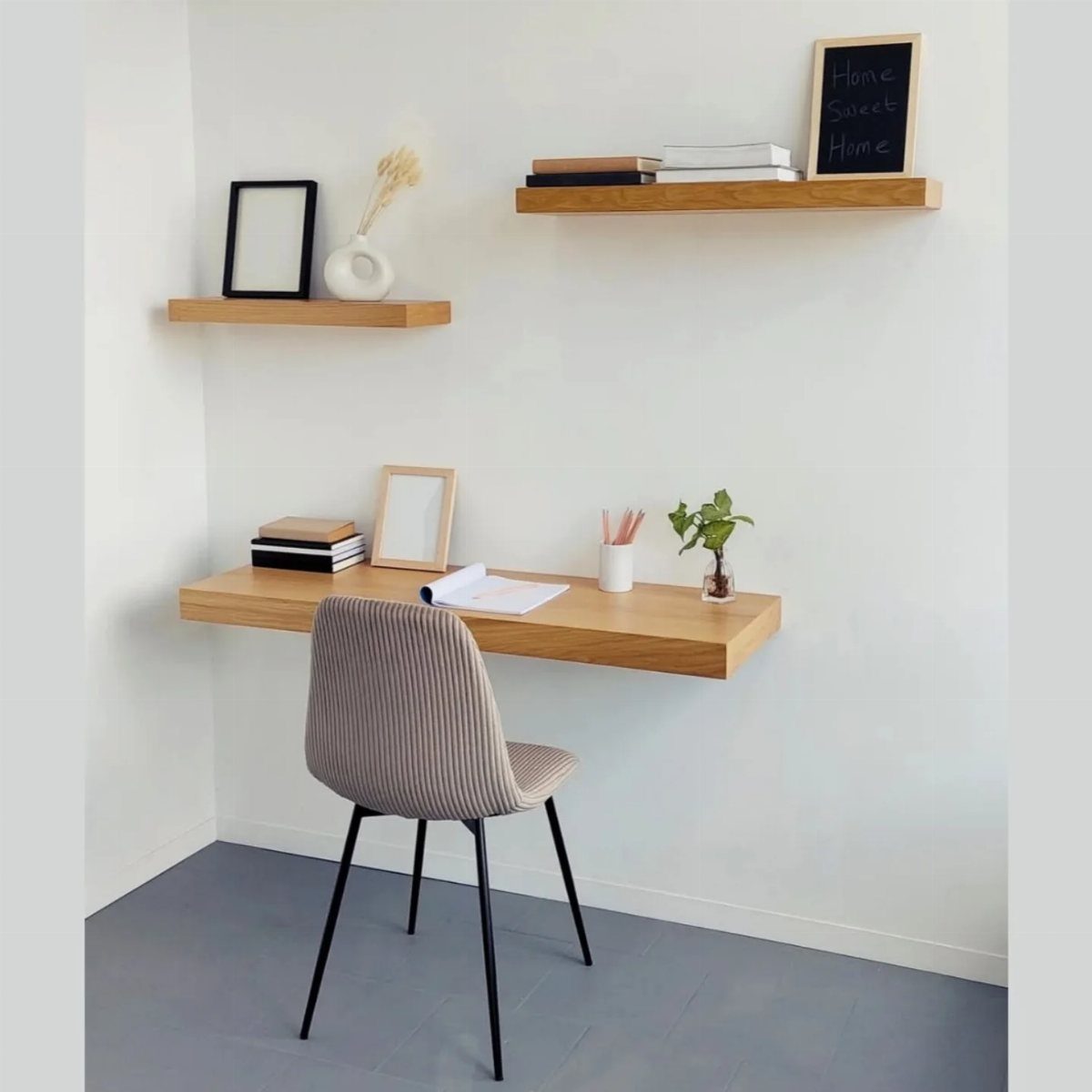 Floating wooden desk with a grey ribbed chair against a white wall.