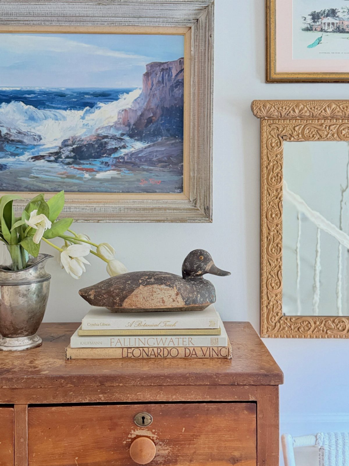 7 Ideas for Wooden Duck Carving, From Decoys to Flight Poses 2 Wooden duck carving on a stack of books next to a silver vase.