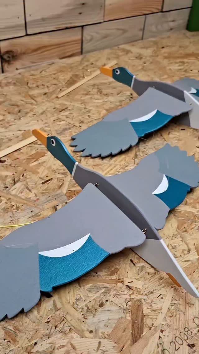 7 Ideas for Wooden Duck Carving, From Decoys to Flight Poses 7 Two painted wooden duck carvings in flight positions on a textured wooden surface.