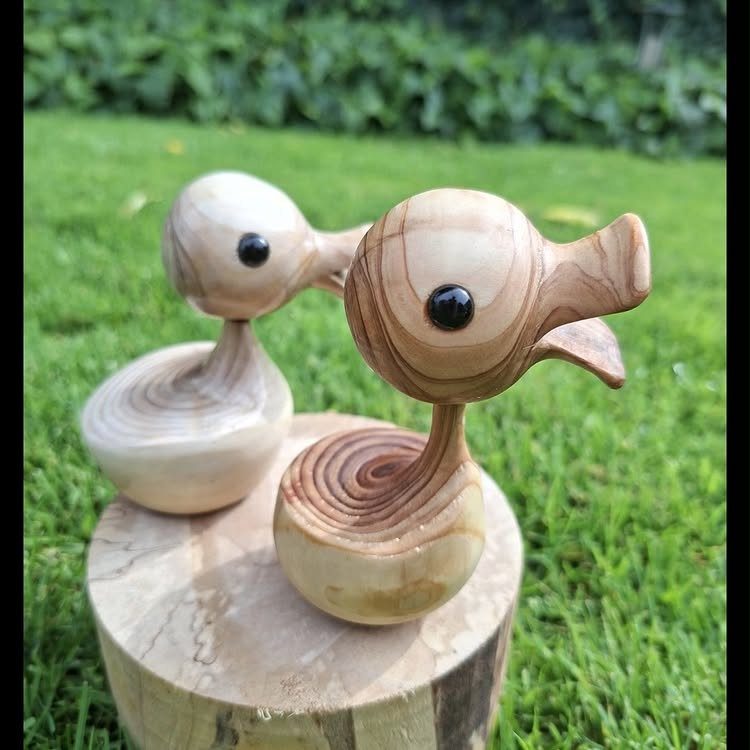 7 Ideas for Wooden Duck Carving, From Decoys to Flight Poses 6 Two polished wooden duck carvings with black eyes on a wooden log slice.