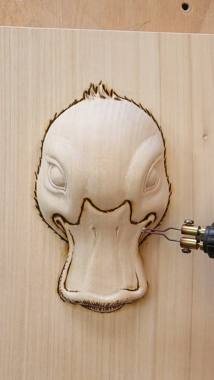 7 Ideas for Wooden Duck Carving, From Decoys to Flight Poses 5 Carved wooden duck head being detailed with a pyrography burning tool.