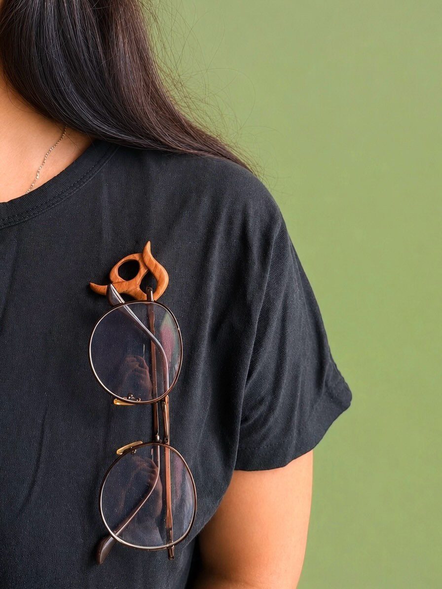Wooden Glasses Holder: 10 Ideas for Every Desk 7 Wooden cat-shaped glasses holder securing round spectacles on a black t-shirt neckline.