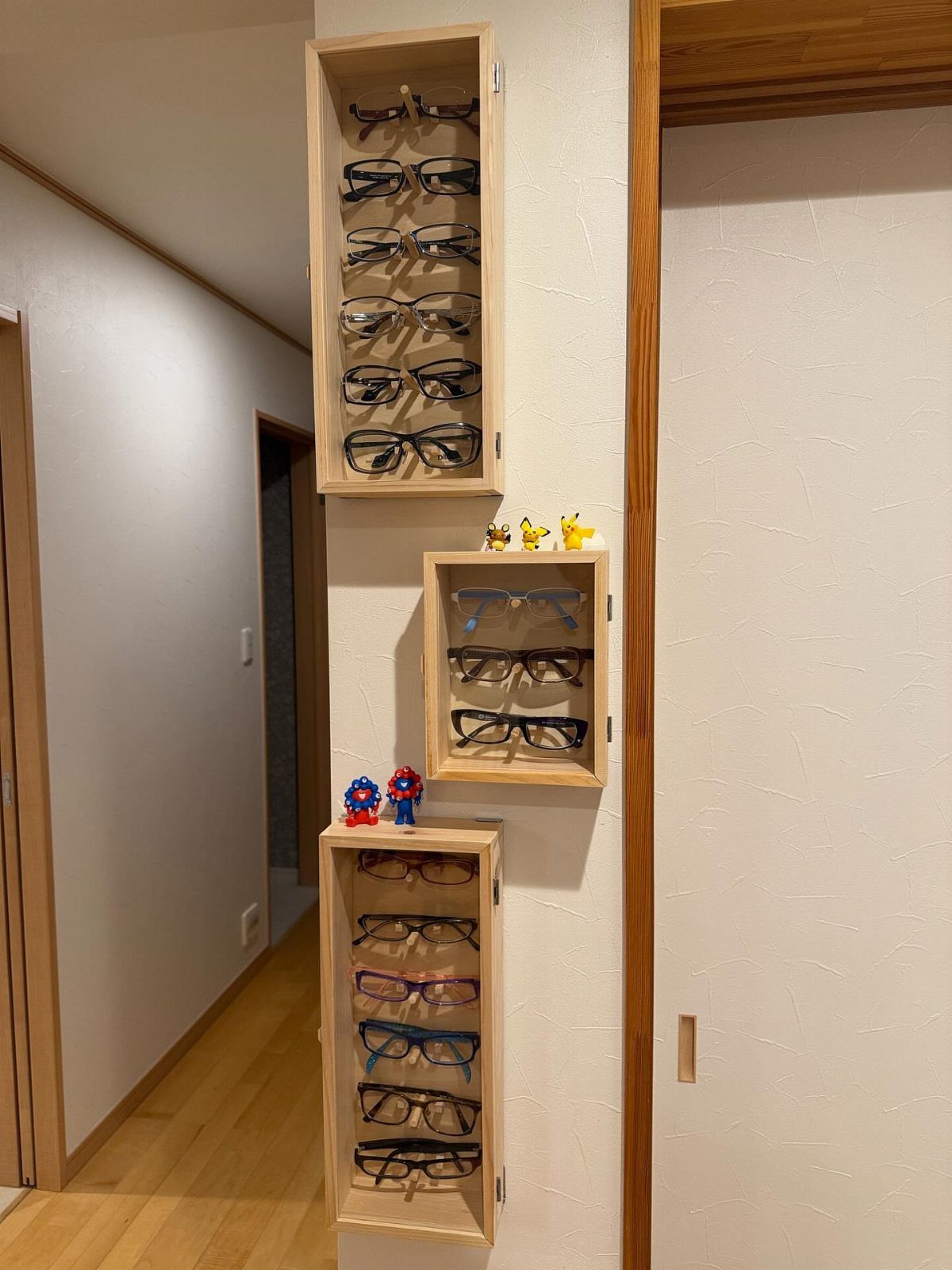 Wooden Glasses Holder: 10 Ideas for Every Desk 6 Wooden wall-mounted storage racks holding several pairs of eyeglasses in a home hallway.