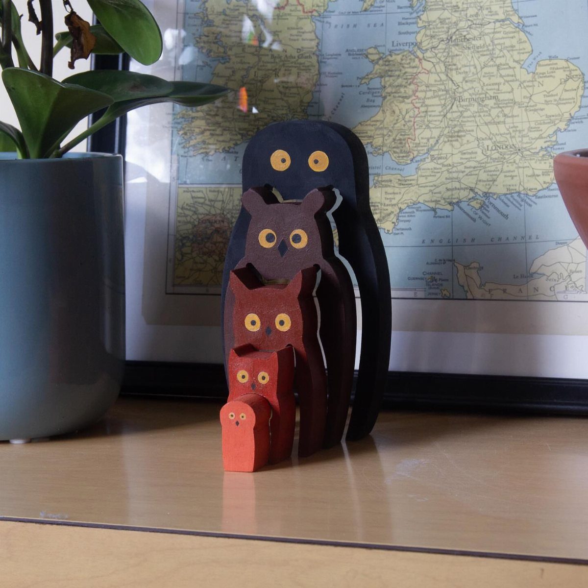 Five nested wooden owl carvings in different colors on a wooden table.
