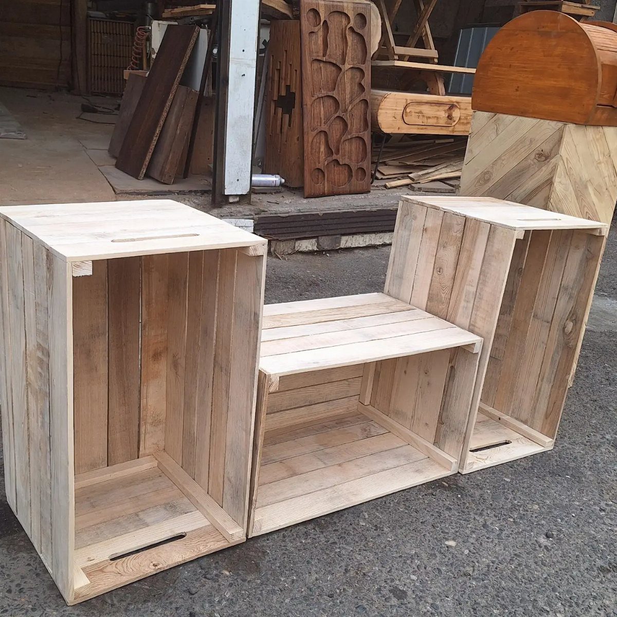 Three different sized wooden pallet crates sitting on a grey asphalt ground.