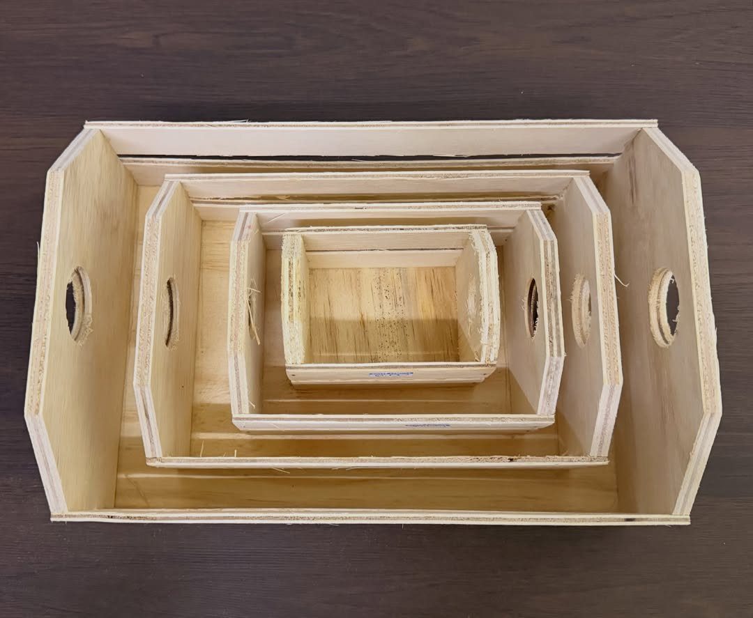 Four light wooden crates nested inside each other on a dark brown background.