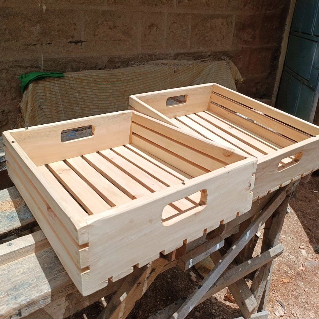 Two small unfinished wooden crates with handle cutouts on a workbench.