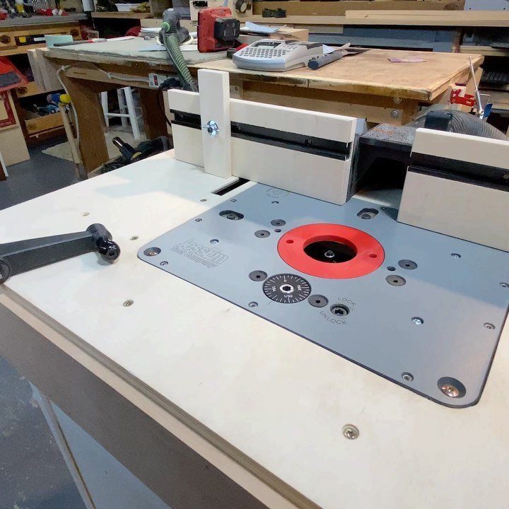 Woodpeckers Router Table Setups: 5 Ideas for Your Shop 5 Woodpeckers router table with a grey insert plate and white fence in a workshop.