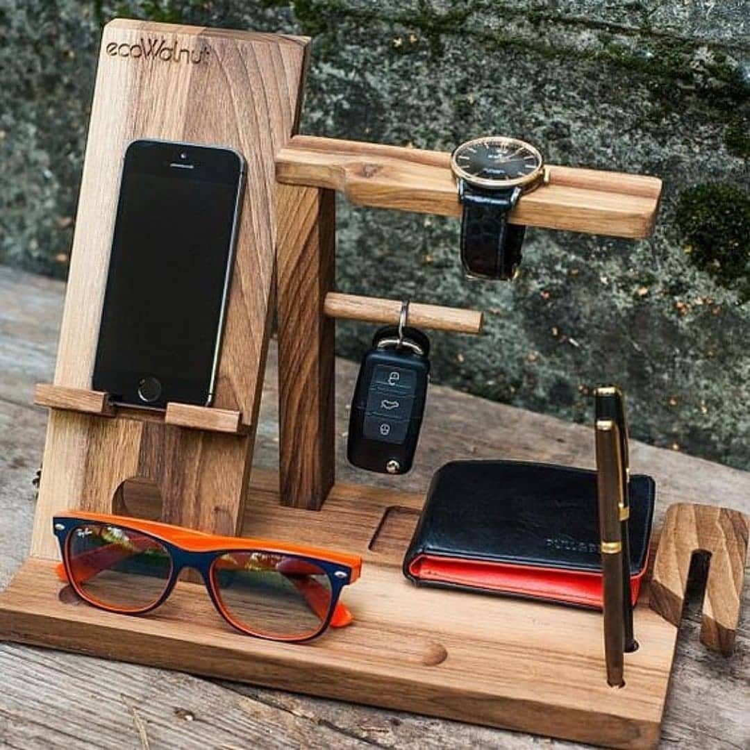 14 Woodworking Ideas to Make Money From Your Shop 12 Wooden docking station holding a smartphone, watch, wallet, keys, and sunglasses outdoors.