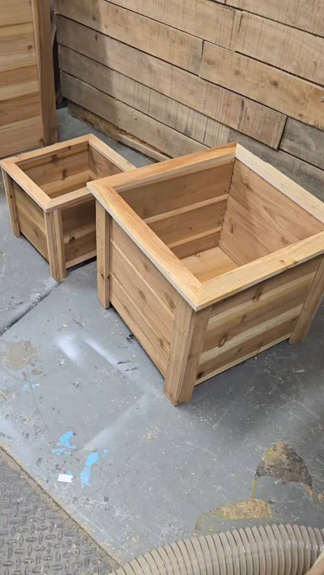 14 Woodworking Ideas to Make Money From Your Shop 8 Two square natural pine wooden planters sitting on a grey concrete workshop floor.