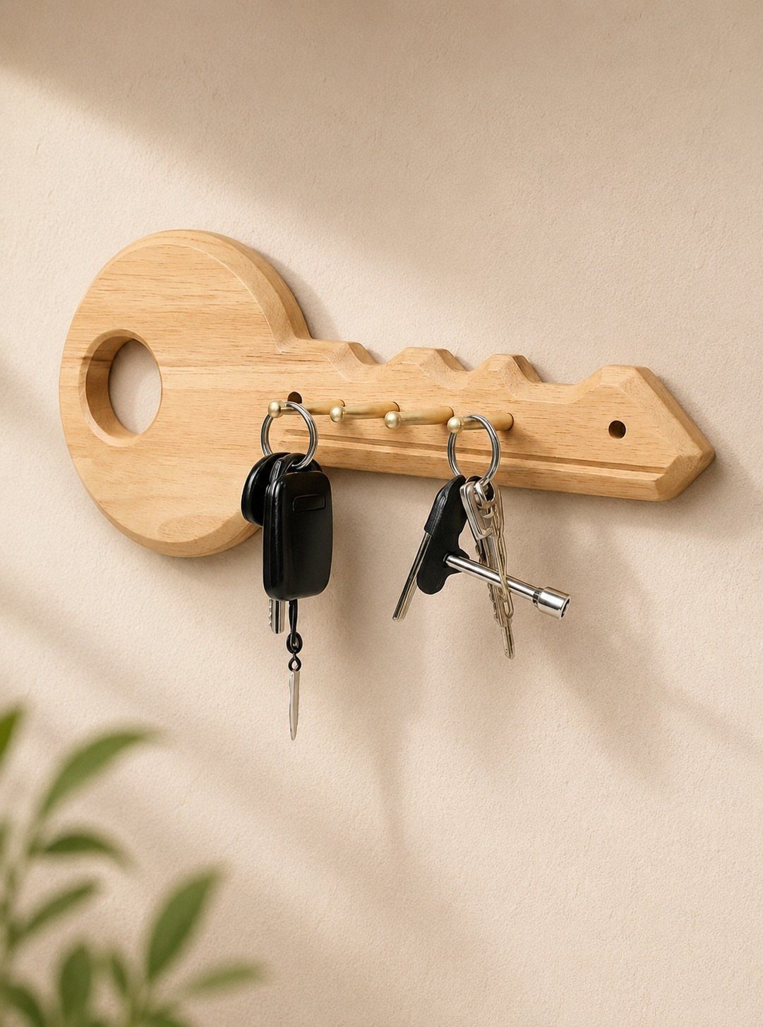 Wooden key holder shaped like a key with metal hooks holding several keys.